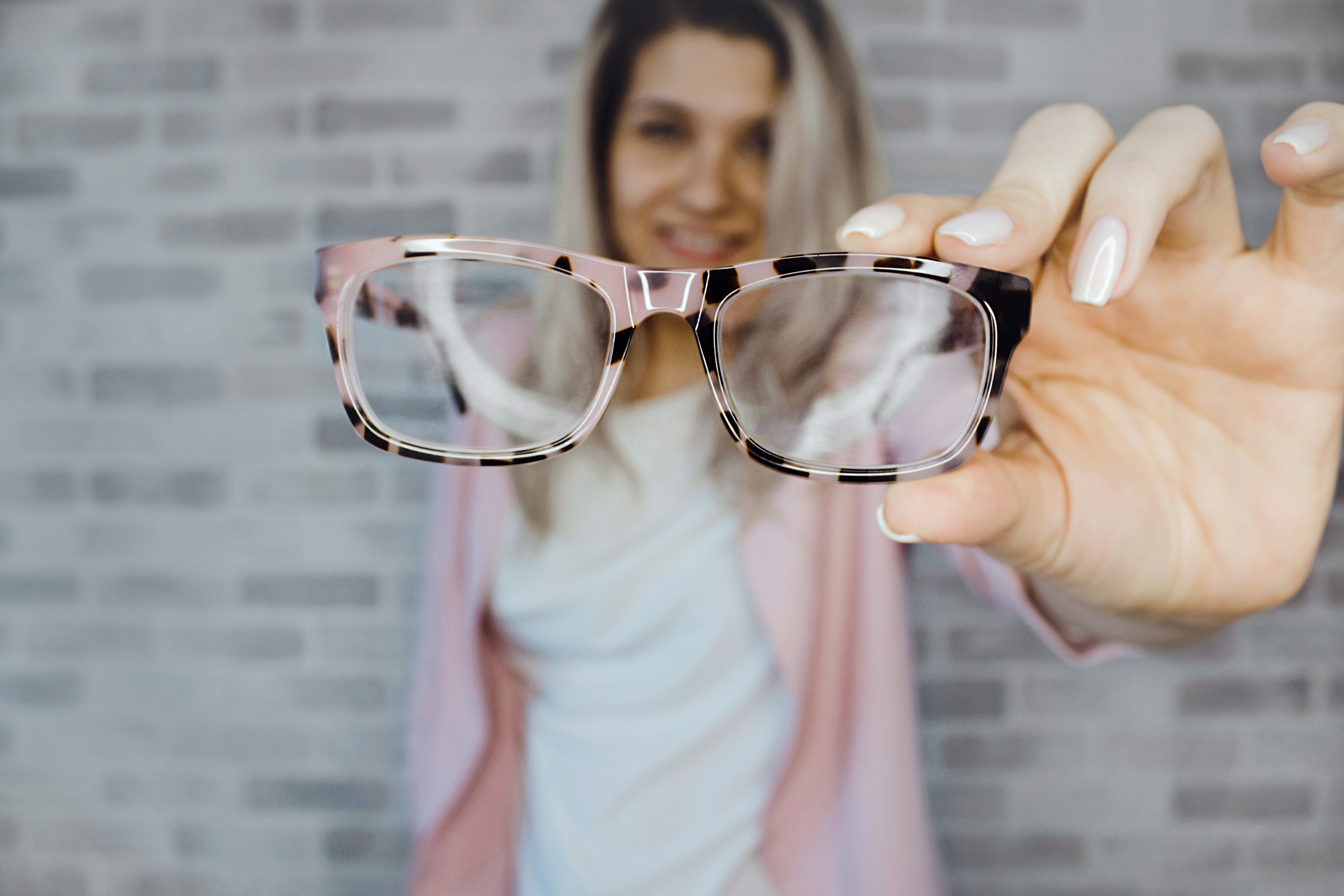 An image of a woman holding her glasses up to the camera. 