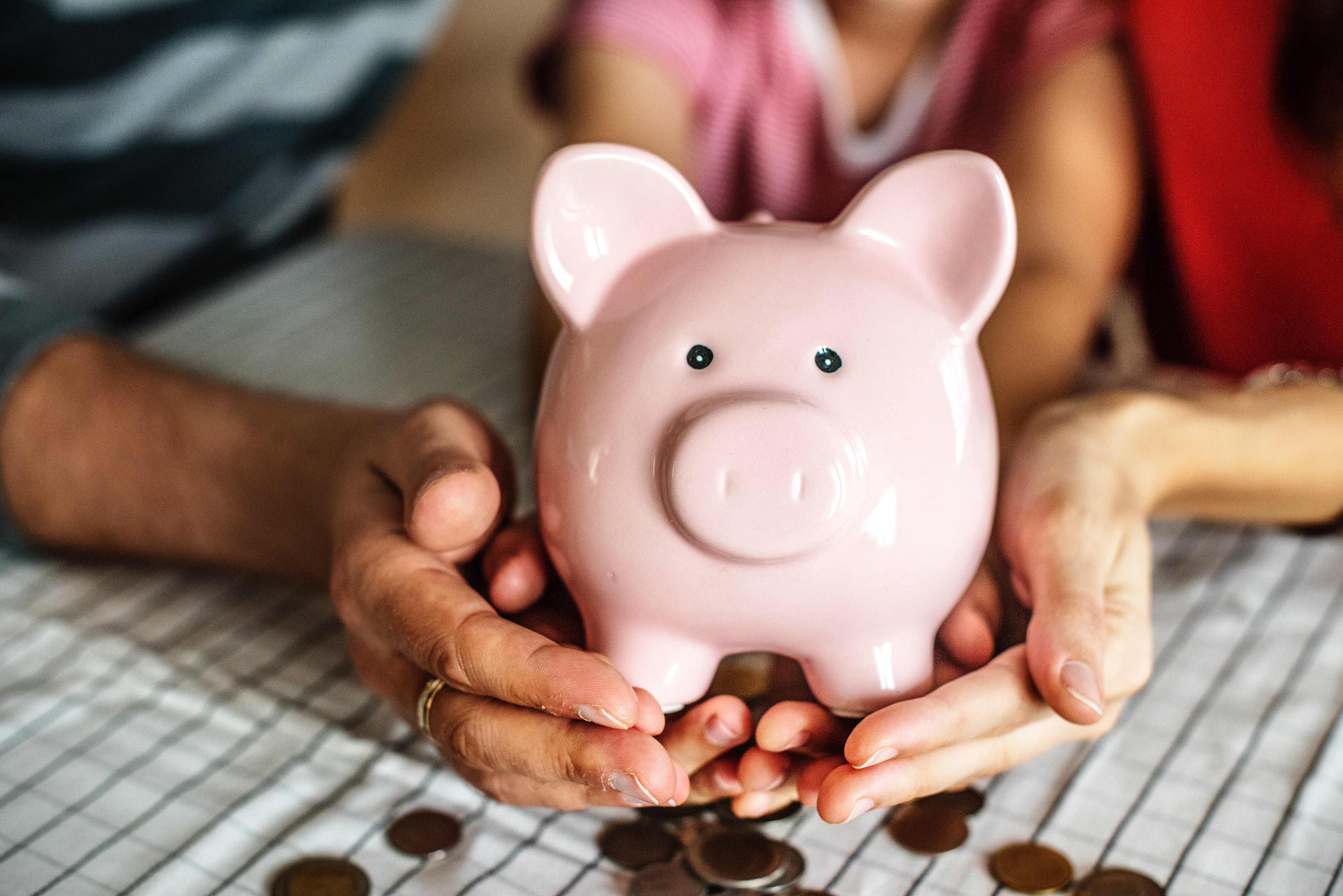 Two individuals with coins in their piggy bank.