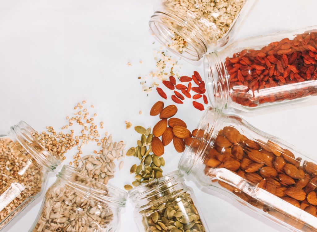 Various nuts, seeds, and grains spilling from jars.