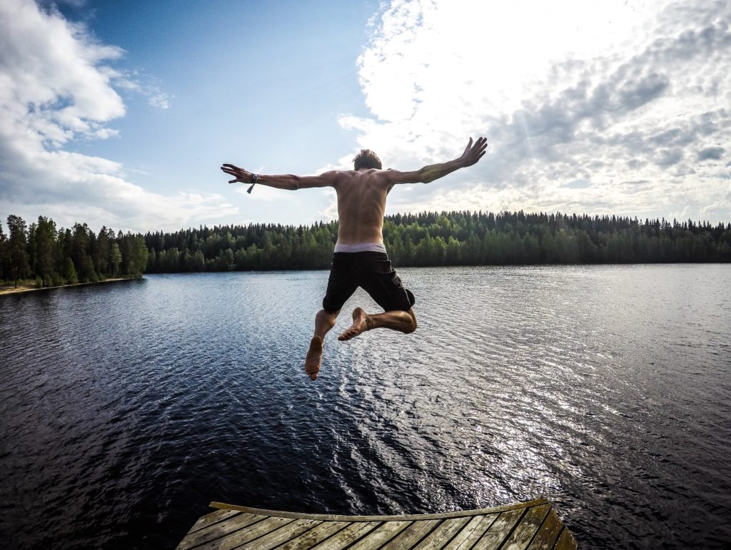 Man jumping into lake off wharf