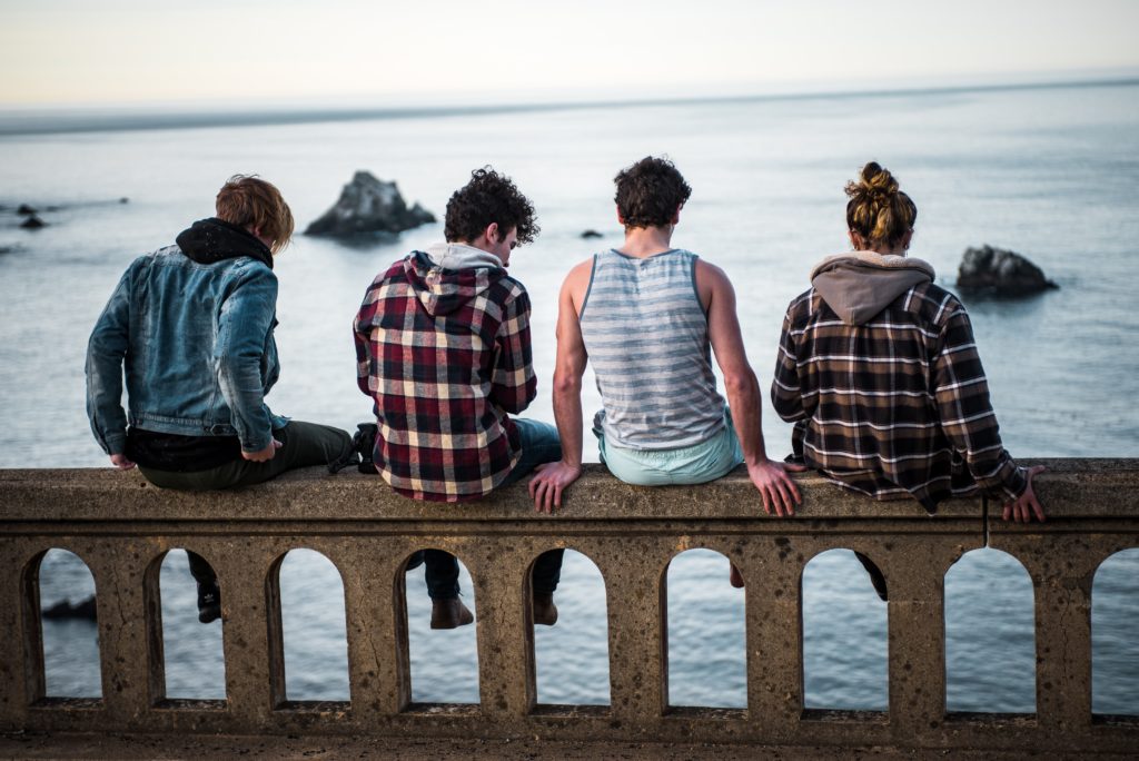 Teenagers sitting on fence overlooking water