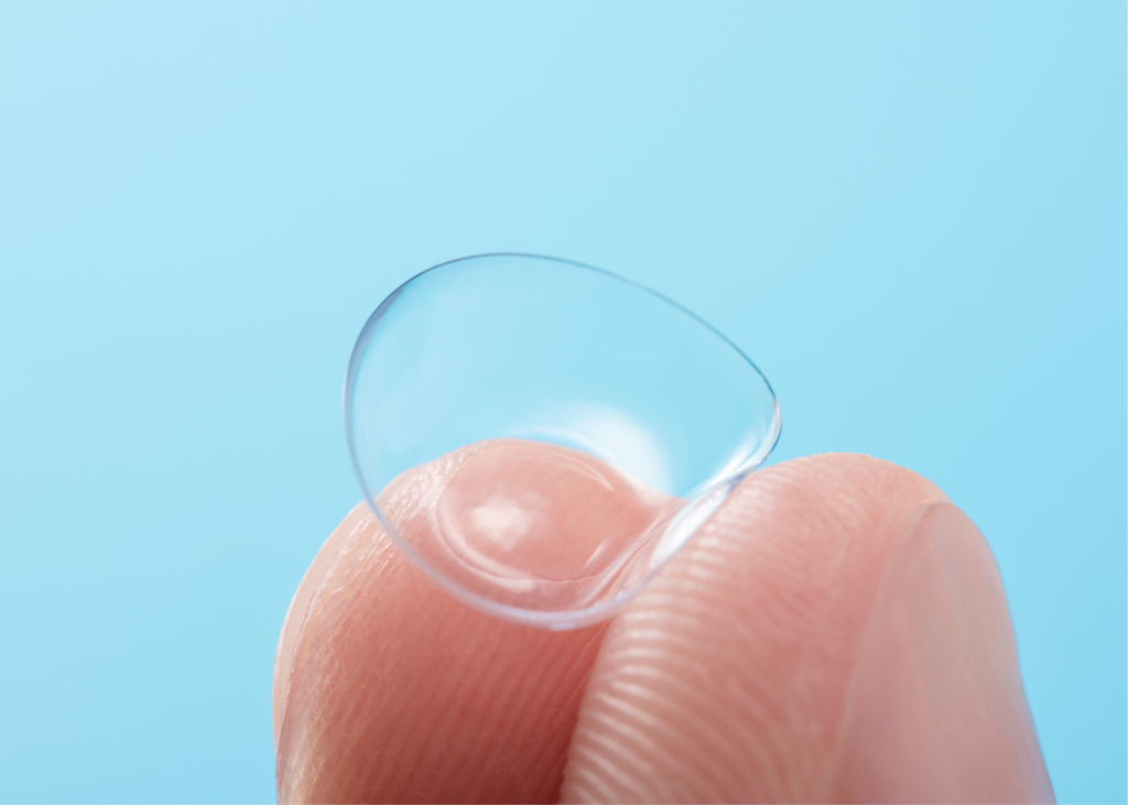 Fingers holding contact lens