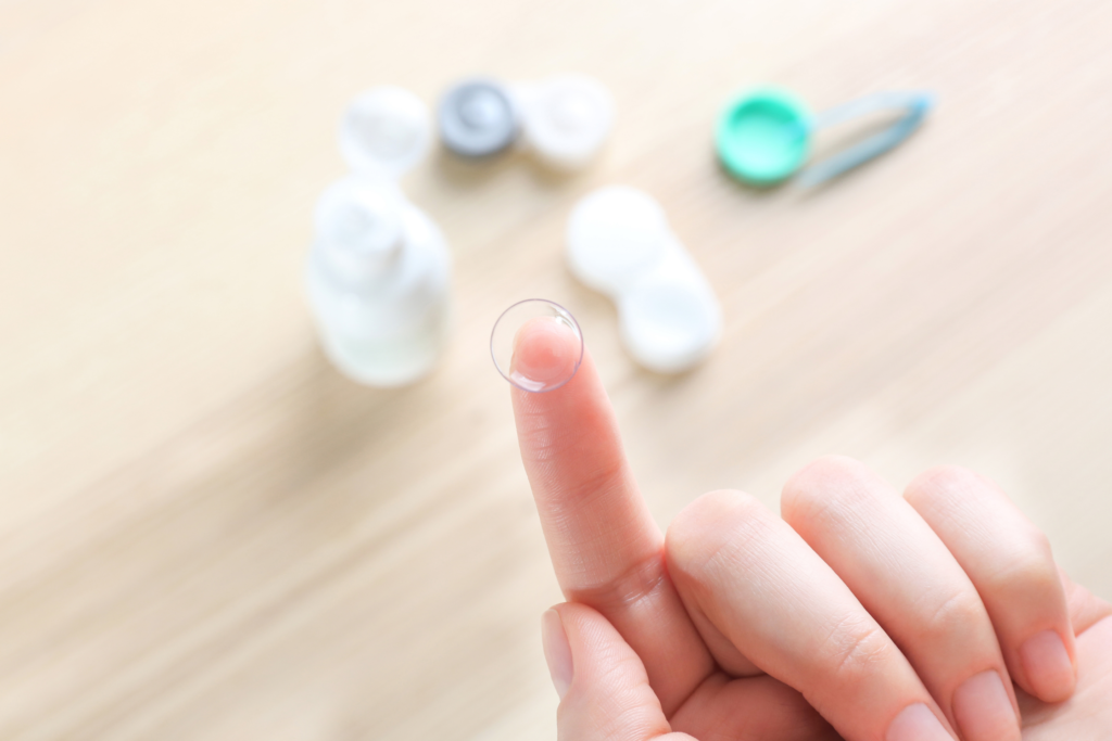 Contact lens on finger with case and solution in background