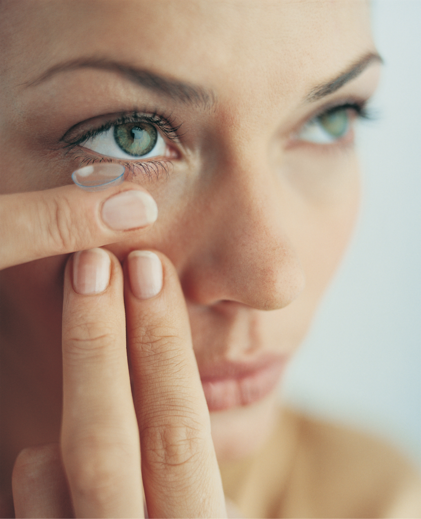 women putting contact lens in eye